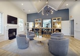 This 1200 square foot single-story community space in Winston-Salem, NC, offers a blend of functionality and style. The exercise room is a standout feature, boasting vaulted ceilings, large windows, and a variety of modern fitness equipment including treadmills, ellipticals, and weight machines. The living area is elegantly designed with high ceilings, a modern chandelier, and comfortable seating arranged around a fireplace, creating a welcoming environment for relaxation and socializing.

The dining area seamlessly connects to the living space, featuring a large wooden table and stylish chairs. A dedicated workspace is equipped with dual-monitor setups and ergonomic seating, perfect for residents needing a productive environment. The space's cohesive design is evident in the consistent use of light wood flooring and a calming color palette of blues and whites throughout.

Large windows and glass doors provide ample natural light and views of the outdoors, enhancing the open and airy feel of the space. The attention to detail is evident in the thoughtful lighting fixtures, artwork, and decorative elements that add character to each area. This multifunctional community space effectively combines comfort, practicality, and aesthetic appeal to cater to various resident needs.