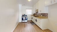 Located at 15003 Lemoli Ave in Gardena, California, this single-story unit offers a clean, functional layout finished with light wood-style flooring throughout. The open living area is bright and spacious, featuring a textured ceiling, warm neutral walls, and natural light streaming through vertical blinds. A low white cabinet partition separates the living space from the adjoining area, adding a subtle architectural detail while maintaining an open feel. A wall-mounted heater unit serves the main living space efficiently.

The kitchen is well-equipped with white cabinetry, a tile mosaic backsplash, a stainless steel gas range, and ample counter space. A window above the sink brings in natural light, and a tall pantry cabinet provides additional storage.

The bedrooms are comfortably sized, each featuring the same light wood flooring, neutral walls, and windows dressed with vertical blinds that allow for generous natural light. The layout provides a sense of privacy and functionality throughout.

The bathroom is neatly appointed with white tile surrounding the tub-shower combination, a white vanity with medicine cabinet mirror, and a frosted window for natural ventilation. The cohesive neutral palette and clean finishes give the entire space a bright, move-in-ready quality.