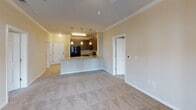 This single-floor residence at 7111 Brandy Run Dr in Mechanicsville, Virginia, presents a well-designed open-concept layout that connects the living area to the kitchen seamlessly. Crown molding lines the ceilings throughout, adding a refined architectural detail, while neutral-toned walls and plush carpeting in the living and bedroom areas create a warm, cohesive atmosphere.

The kitchen is a functional centerpiece, featuring dark wood cabinetry, granite countertops, and black appliances including a refrigerator, range, and built-in microwave. A peninsula with pendant lighting provides additional workspace and casual dining potential, while light wood-style flooring grounds the space with a clean, contemporary feel.

The bathrooms are well-appointed with granite-topped dark wood vanities, light wood-style flooring, and ample storage. One bathroom includes a tub-shower combination with tiled surround, while another features a glass-enclosed shower with grab bars. Both offer large mirrors and generous counter space.

A dedicated in-unit laundry area accommodates a stacked washer and dryer conveniently located near the kitchen. Spacious walk-in closets with wire shelving provide substantial storage. A carpeted room with French doors and a ceiling fan offers access to the outdoors and abundant natural light, enhancing the overall openness of the home.