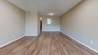 Located at 1828 W 18th St N in Wichita, Kansas, this single-story residence offers a well-organized layout with a cohesive, neutral aesthetic throughout. The living room serves as a central gathering space, highlighted by a tiled fireplace with a wood mantel, recessed lighting, and sliding glass doors that open to an outdoor balcony, allowing natural light to fill the room. Durable wood-look flooring runs throughout the main living and kitchen areas, adding warmth and easy maintenance.

The kitchen features white shaker-style cabinetry, a white subway tile backsplash, light countertops, a stainless steel dishwasher, and a pass-through window that connects visually to the living space. Adjacent areas transition into carpeted bedrooms, each finished with neutral tones and window blinds that provide natural light and privacy. One bedroom includes a built-in closet with double doors, while the primary bedroom offers direct access to a vanity area.

The bathrooms are functional and clean in design. One includes a tiled tub-shower combination with a window, while another features a white-tiled walk-in shower. Wood-look flooring carries through both bathrooms. Textured ceilings are present throughout, contributing to the home's classic residential character.