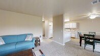 This single-floor unit at 1426 NE 105th Way in Hillsboro, Oregon offers a practical and comfortable layout designed for everyday living. The open living area is finished with plush carpeting and neutral wall tones, creating a warm, inviting atmosphere. A ceiling fan with integrated lighting adds airflow and functionality to the space.

The kitchen is well-appointed with abundant white cabinetry offering generous storage, light-toned countertops, and a full suite of white appliances including a refrigerator, electric range, built-in microwave, and dishwasher. Tile flooring throughout the kitchen adds durability and easy maintenance.

The dining area connects seamlessly to a sliding glass door that opens to a private balcony overlooking a green outdoor setting, allowing natural light to fill the space. Two carpeted bedrooms provide comfortable retreats, each with closet space. The primary bedroom features a ceiling fan and a large window.

The bathroom includes a full tub-shower combination with tile flooring and a vanity with storage. A notable convenience is the in-unit laundry area, positioned just off the bathroom hallway, adding practical day-to-day functionality to this well-organized Hillsboro residence.