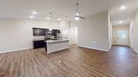 Located at 515 Buck Trail in Warsaw, Indiana, this single-floor home is designed with a cohesive, modern aesthetic and practical layout. The open-concept kitchen and living area serves as the heart of the home, featuring soaring vaulted ceilings, rich hardwood-style flooring, and pendant lighting above a central island. Dark espresso cabinetry lines the kitchen walls, complemented by granite-look countertops and a full suite of stainless steel appliances, including a refrigerator, range, and microwave. A walk-in pantry with built-in shelving provides generous storage just off the kitchen.

The living area extends naturally from the kitchen, offering vaulted ceilings, a ceiling fan, and sliding glass doors that invite natural light and outdoor access. Bedrooms are carpeted for comfort, each featuring ceiling fans and windows with outdoor views of the surrounding neighborhood. The primary bathroom includes a double-sink vanity with granite-style countertops, a walk-in shower, and an adjacent walk-in closet with wire shelving. A secondary bathroom offers a tub-shower combination and matching dark cabinetry. Hardwood-style flooring runs consistently through the main living areas, tying the home's clean, contemporary design together.
