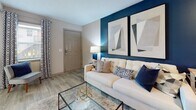 Located at 6407 Old Madison Pike NW in Huntsville, Alabama, this single-story unit offers a thoughtfully arranged floor plan that balances comfort and functionality. The living room serves as the centerpiece of the space, featuring light wood-style flooring, a textured ceiling, and a bold navy accent wall adorned with large-format artwork. The open layout allows for a clear sightline into the kitchen, creating a connected and airy feel throughout the common areas.

The kitchen is outfitted with white shaker-style cabinetry, granite-look countertops, a stainless steel sink, and stainless steel appliances including a range, microwave, and refrigerator. Light flooring continues throughout, maintaining visual consistency across the space.

The bedroom is generously proportioned, featuring multiple windows that invite abundant natural light, patterned drapery, a ceiling fan, and a wall-mounted HVAC unit. Light wood flooring carries through this room as well, contributing to the cohesive aesthetic.

The bathroom includes a tub-shower combination with a decorative curtain and wood-style flooring. A dedicated laundry area houses a full-size front-loading LG washer and dryer alongside a Whirlpool water heater, providing essential in-unit utilities conveniently within the space.