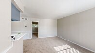 Located at 855 Greens Rd in Houston, TX, this one-bedroom, one-bathroom unit offers a practical and well-organized single-floor layout. The living room is bright and welcoming, featuring plush carpeting, a large window that allows natural light to fill the space, and a pass-through opening that connects to the kitchen, enhancing the open feel between the two areas. The kitchen is efficiently designed with wood-look flooring, blue-gray cabinetry, a white electric range, a full-size refrigerator, and a window that brings in additional natural light. The spacious bedroom is carpeted and features a ceiling fan with light fixture, a window with outdoor views, and direct access to a dedicated closet equipped with a full-width hanging rod — providing ample storage. The bathroom includes a tiled shower-tub combination and clean white fixtures throughout. Neutral tones dominate the interior, with light gray walls, white trim, and beige carpeting creating a cohesive and understated aesthetic. The layout is compact yet functional, making efficient use of every room while maintaining a comfortable and livable atmosphere throughout.