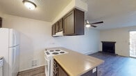 This single-floor unit offers a practical and functional layout designed for comfortable everyday living. The kitchen serves as a central feature, equipped with dark espresso-toned cabinetry, a peninsula counter with a light-toned laminate surface, a white electric coil range, dishwasher, and refrigerator. A ceiling fan with a light fixture overhead connects the kitchen to the open living area, which is finished with durable wood-look laminate flooring and a baseboard heating unit along the wall. The living space is bright and open, with clean white walls that enhance the sense of space.

A bedroom features carpeted flooring, a window with blinds that allows natural light, a baseboard heater, and a wall-mounted air conditioning unit for year-round climate control. A separate room with sliding glass doors and wood-look flooring offers additional versatile living space with access to the outdoors.

The bathroom includes a full tub and shower combination with tiled surround, a toilet, and a grab bar, finished in neutral tones. Throughout the unit, textured ceilings and neutral wall colors provide a clean, understated backdrop. The floor plan, as seen from the dollhouse view, presents a compact yet well-organized layout that efficiently utilizes the available space.