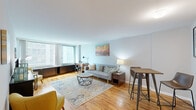 This single-floor residence offers a thoughtfully designed layout that balances comfort and functionality across its key living spaces. Warm hardwood flooring flows continuously throughout, lending a cohesive and inviting character to the entire unit.

The living room serves as the centerpiece of the space, featuring large floor-to-ceiling windows that flood the room with natural light and offer outward views of the surrounding cityscape. The open, airy atmosphere is enhanced by neutral-toned walls and ample room for a variety of furniture arrangements, including a dedicated area suitable for a home workspace.

The kitchen is efficiently arranged in an L-shaped configuration and is equipped with light maple cabinetry, dark granite countertops, a double-basin stainless steel sink, and stainless steel appliances including a refrigerator, gas range, and built-in microwave. A partial wall separates the kitchen from the living area while maintaining an open feel.

The bedroom is a serene, well-proportioned retreat with a large window providing natural light and city views. It features mirrored sliding closet doors that enhance the sense of space.

The bathroom is clean and functional, finished with white tilework, a vanity with a wide mirror, and a shower-tub combination. Together, these spaces form a complete and well-maintained residence.