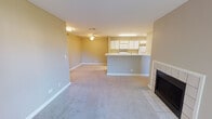 Located at 1261 Deerfield Pkwy in Buffalo Grove, IL, this single-floor unit offers a well-organized layout with a neutral color palette and practical finishes throughout. The open-concept living and dining area is a central highlight, featuring soft carpeting, a ceiling fan, and a tile-surround fireplace that anchors the space. A peninsula counter connects the living area to the kitchen, providing a natural division while maintaining an open feel.

The galley-style kitchen is efficiently designed with white cabinetry featuring gold-tone hardware, white appliances including a range, microwave, refrigerator, and dishwasher, and light wood-look flooring. Ample counter space and overhead lighting make this a functional cooking area.

The bedrooms are carpeted and generously proportioned, each receiving natural light through windows with views of surrounding greenery. One bedroom includes a sliding glass door opening to a private balcony with outdoor views, while another features a connected en-suite bathroom with a glass-enclosed walk-in shower and built-in cabinetry. A second full bathroom offers a tub-shower combination with white tile surround and a vanity with integrated sink. The overall ambiance is clean, understated, and move-in ready.