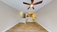 This two-floor residence is thoughtfully designed with a clean, neutral aesthetic throughout. The main living area on the lower level features durable wood-look tile flooring and is anchored by a ceiling fan overhead. A split-level layout connects the living space to the kitchen via a half-wall partition, with staircases providing access both above and below. The kitchen is well-appointed with white shaker cabinetry, white subway tile backsplash, light stone countertops, and a full suite of stainless steel appliances, including a range, over-the-range microwave, and refrigerator.

The bathrooms carry a consistent design language, featuring floor-to-ceiling white subway tile. One bathroom includes a soaking tub with tiled surround, while another offers a glass-enclosed walk-in shower with a penny-tile floor and brushed nickel fixtures.

The upper level houses generously sized bedrooms finished with plush carpeting, ceiling fans, and access to walk-in closets. One bedroom features sliding glass doors opening to a private balcony with outdoor views, while another room offers similar balcony access alongside an arched wall niche. A staircase with wood-look treads and a dark metal handrail connects both levels, with natural light filtering in from above.
