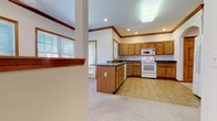 Located at 95 Hockanum Blvd in Vernon Rockville, Connecticut, this three-floor home offers a thoughtfully designed layout with consistent warm-toned woodwork and crown molding throughout. The kitchen is a functional centerpiece, featuring oak cabinetry with arched detailing, dark granite-style countertops, tile flooring, recessed lighting, and white appliances including a range, microwave, and dishwasher. A peninsula provides additional prep and storage space, while multiple windows allow natural light to fill the room. An elegant arched doorway connects the kitchen to adjoining areas. The living spaces are finished with plush wall-to-wall carpeting and rich wood trim, maintaining a cohesive and inviting aesthetic. Bedrooms are generously proportioned, each with large windows offering neighborhood views, ceiling fans, and solid wood panel doors. One bedroom includes a spacious walk-in closet outfitted with built-in shelving and hanging rods, providing substantial storage capacity. Bathrooms are cleanly finished with tile flooring, oak vanities, and simple, classic fixtures. A half bath features an oval wood-framed mirror above the vanity. The lower level presents an open, unfinished space with concrete floors and exposed infrastructure, offering significant potential for customization or additional living area.