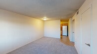 Located at 718 W 49th Street in Tulsa, Oklahoma, this single-floor residence offers a practical and well-organized layout with two bedrooms and two full bathrooms. The living area features neutral-toned carpet underfoot and a textured ceiling, creating a simple and functional space that opens directly toward the kitchen. The galley-style kitchen is efficiently designed with warm wood cabinetry, stone-look countertops, and light tile flooring. It is equipped with a white electric range, dishwasher, and refrigerator, with ample upper and lower cabinet storage on both sides. Both bathrooms include a tub/shower combination with white tile surround, tile flooring, wood vanity cabinetry, and stone-look countertops, with grab bars installed for added accessibility. The primary bedroom is generously sized and includes a closet, while the second bedroom features a window that allows natural light to filter in and its own closet with a built-in hanging rod. A hallway connects the main living spaces to the bedrooms, and an additional closet provides extra storage. The textured ceilings are consistent throughout, giving the unit a cohesive finish. Overall, the space offers a straightforward, functional design well-suited for comfortable everyday living.
