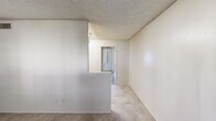 Located at 844 East Bell Road in Phoenix, AZ, this single-floor, one-bedroom, one-bathroom unit offers an efficient and functional layout. Neutral-toned tile flooring runs throughout the space, complemented by light beige walls and textured ceilings that create a clean, consistent look.

The living room greets you at the entry, featuring a front-facing window that allows natural light to filter in, brightening the open area. A half-wall partition separates the living space from the adjoining dining and kitchen area, providing subtle definition without closing off the floor plan.

The galley-style kitchen is lined with wood-toned cabinetry on both sides, offering ample upper and lower storage. Light countertops provide workspace, and the kitchen includes a stainless steel sink, dishwasher, range, and a full-size refrigerator.

The bedroom is a well-proportioned private retreat featuring dual side-by-side sliding closets with built-in hanging rods and shelving, providing generous storage options. The full bathroom includes a vanity with a dark countertop, a toilet, and a tub/shower combination with light-paneled surround walls. A hallway connects the main living areas to the bedroom and bathroom, completing the straightforward and practical layout of this Phoenix residence.
