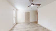 This two-story space is designed with a neutral, light-filled aesthetic throughout. The main living areas feature light wood-look laminate flooring that lends a clean, modern feel, while the bedrooms are fitted with plush gray carpet for added comfort. Ceiling fans are present in every room, providing both practical airflow and ambient lighting.

The bedrooms are generously proportioned, each offering multiple windows fitted with horizontal blinds that allow natural light to filter in while maintaining privacy. Several bedrooms include double closets, providing ample storage space. The textured ceilings add a subtle architectural detail consistent across the living areas.

The bathrooms are well-appointed, featuring warm wood cabinetry paired with granite-patterned countertops and undermount sinks with brushed nickel fixtures. Large mirrors and multi-bulb vanity lighting enhance brightness. One bathroom includes a full tub-shower combination with clean white tile surround, while another bathroom opens directly into an adjoining bedroom, functioning as an en suite. The overall palette of the space is cohesive, utilizing soft creams and beiges that contribute to a calm, welcoming atmosphere throughout all levels.