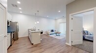 Located at 1866 E 93rd St in Cleveland, OH, this well-appointed one-bedroom, one-bathroom unit offers a thoughtfully designed open-concept layout with modern finishes throughout. Light-toned hardwood-style flooring flows seamlessly through the main living areas, creating a clean and cohesive aesthetic.

The kitchen is a standout feature, showcasing white cabinetry, granite countertops, stainless steel appliances including a French door refrigerator, electric range, and microwave, as well as a peninsula island with bar seating illuminated by sleek pendant lighting — ideal for casual dining or entertaining.

The kitchen opens directly into the living room, which benefits from natural light streaming through a large sliding glass door fitted with vertical blinds. The bedroom is carpeted for comfort, featuring windows with outdoor views and ample space for a full furnishing arrangement.

The bathroom maintains a clean, modern look with large-format tile flooring, a white vanity with storage drawers, a well-lit mirror, and a shower-tub combination. A dedicated in-unit laundry room with a stacked washer and dryer adds significant convenience. Recessed lighting and a neutral color palette of soft whites and warm grays tie the entire space together with a fresh, contemporary feel.