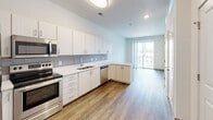 Located at 4359 Sadler Rd in Glen Allen, Virginia, this single-floor residence offers a thoughtfully designed layout with modern finishes throughout. The open-concept kitchen serves as a central feature of the space, outfitted with white cabinetry extending to the ceiling, a gray tile backsplash, white quartz countertops, a stainless steel sink, and a full suite of stainless steel appliances including a refrigerator, electric range, microwave, and dishwasher. Wood-style plank flooring runs through the kitchen and living areas, lending warmth and continuity to the space.

The living area flows naturally from the kitchen and opens to a private balcony through a sliding glass door, allowing natural light to fill the interior. The bedroom features plush wall-to-wall carpeting, a generous window with horizontal blinds, and access to a walk-in closet with built-in shelving. An ensuite bathroom is accessible directly from the bedroom and includes a tub-shower combination, tile flooring, built-in shelving, and a vanity with white cabinetry.

The overall aesthetic is clean and contemporary, characterized by neutral tones, recessed lighting, and a well-organized floor plan that maximizes functionality and comfort throughout the residence.