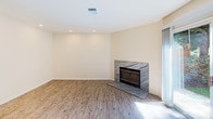 Located at 4850 Talmadge Park Row in San Diego, CA 92115, this three-story home offers a clean, modern aesthetic throughout its well-appointed layout. The main living area features light wood-style luxury vinyl plank flooring and a bright, open feel, with natural light streaming through blinds-covered windows. The adjoining dining area is illuminated by a pendant light fixture, and transitions seamlessly into the kitchen, which is outfitted with white shaker cabinets, granite countertops, and a full suite of white appliances including a gas range, over-range microwave, and side-by-side refrigerator. Bedrooms are carpeted in neutral tones and receive generous natural light through large windows with views of surrounding greenery. The primary bedroom connects directly to an en suite bathroom featuring a dual-sink vanity with granite countertops, white cabinetry, and a walk-in closet with built-in shelving. Additional bathrooms include tiled tub-and-shower combinations with brushed nickel fixtures. The home also includes a spacious attached garage with an automatic opener and interior access door, providing ample storage and parking. Throughout, the home maintains a consistent palette of warm whites and neutral tones, creating a cohesive and inviting atmosphere.
