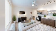Located at 340 Legion Dr in Lexington, KY, this efficient one-bedroom, one-bathroom unit offers a well-designed open-concept layout that maximizes every square foot. Light-toned luxury vinyl plank flooring runs throughout, complementing the crisp white walls and creating a clean, modern aesthetic.

The living and dining area flows seamlessly into the kitchen, which is appointed with warm-toned shaker-style cabinetry, white quartz countertops, a stainless steel sink, and a full suite of stainless steel appliances including a refrigerator, electric range, microwave, and dishwasher. An open metal shelf above the counter adds an industrial touch and additional display space. Track lighting overhead ensures the kitchen is well-lit.

The living area accommodates both a seating arrangement and a dining space, anchored by a ceiling fan with integrated lighting. The open sightlines between the living area and the spacious bedroom make the unit feel larger than expected.

The generously sized bedroom features a ceiling fan, a large window that invites natural light, and ample room for a full furniture arrangement including a bed and seating area.

The bathroom is neatly finished with a sliding glass shower/tub enclosure, a wood-toned vanity with a white countertop, and a framed mirror—completing this thoughtfully designed residence.