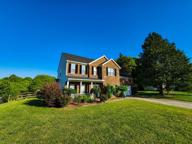 Charming front view with brick facade, porch, and landscaped front yard. - 7801 Peach Blossom Ct
