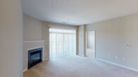 Located at 12251 Elm Forest Ct, Unit F in Clarksburg, MD, this single-floor residence offers a well-designed layout with a neutral color palette and an abundance of natural light throughout. The spacious living room is a standout feature, anchored by a classic fireplace with a clean white mantle and flanked by large floor-to-ceiling sliding glass doors dressed with vertical blinds, allowing generous daylight and outdoor views to fill the room. Soft carpeting extends throughout the living and bedroom areas, adding warmth and comfort underfoot. Adjacent to the living room, a dedicated dining area is illuminated by a pendant light fixture and flows seamlessly into the kitchen. The kitchen features warm honey-toned wood cabinetry, laminate countertops, hardwood-style flooring, black appliances including a gas range, built-in microwave, and refrigerator, along with a stainless steel sink beneath a pendant light. The bedrooms are bright and comfortable, with carpeted floors and windows offering leafy outdoor views. The bathrooms include wood-toned vanities with white countertops and large mirrors. A dedicated in-unit laundry area with a full-size washer and dryer adds everyday convenience to this functional and inviting home.