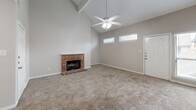 Located at 11240 Perry Rd in Houston, TX, this multi-story home offers 2 bedrooms and 3 bathrooms across three floors. The main living level serves as the heart of the home, where a dramatic vaulted ceiling with an exposed beam and ceiling fan crowns a spacious living room anchored by a classic brick fireplace. Neutral carpet flooring flows throughout the living areas, complementing the soft, neutral wall tones. Natural light enters through well-placed windows, adding to the open, airy feel. The adjacent kitchen is well-appointed with warm wood cabinetry, granite-look countertops, a central island for additional prep space, tile flooring, and white appliances including a range, microwave, dishwasher, and refrigerator. The dining area connects seamlessly to the kitchen and living space. Both bedrooms are carpeted and include ceiling fans; the primary bedroom features a private en-suite bathroom with a wood-toned vanity and granite countertop. Additional bathrooms include a tiled tub-shower combination. Multiple closets and pantry spaces provide ample storage throughout. The attached garage offers a clean, epoxy-coated floor and automatic opener. Multiple staircases connect the three levels efficiently, completing this functional and comfortable Houston home.