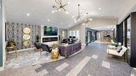 The Retreat at River Ranch clubhouse is a single-floor amenity space designed with a refined, contemporary aesthetic. The entrance greets visitors with a dramatic floor-to-ceiling marble feature wall bearing the property's signature logo, accented by elegant pendant lighting and lush snake plants set in a river rock planter with a geometric-patterned base. Large glass-paned doors and partitions allow sightlines throughout the space, creating an open and connected atmosphere.

The main lounge is an expansive, light-filled gathering area anchored by a sleek linear fireplace set within a marble surround and framed by patterned accent wallcovering. A large wall-mounted television sits above the fireplace, complementing plush seating arrangements that include a tufted velvet sofa, leather chairs, and gold accent tables. Striking sputnik chandeliers hang overhead, adding a bold mid-century modern touch.

Adjacent to the lounge is a dedicated game room featuring a full-size billiards table and vibrant contemporary artwork. This area flows directly into a bar nook adorned with a dramatic tropical botanical wallcovering, bar seating along a white countertop, and open shelving. A glass-enclosed fitness center with cardio and strength equipment rounds out the amenities, bathed in natural light from large exterior-facing windows throughout.