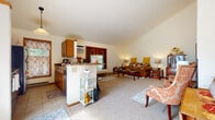 Located at 7641 Carrington Dr in Madison, Wisconsin, this single-floor home offers a well-designed layout that balances open communal spaces with private retreats. The heart of the home is a spacious open-concept living and dining area characterized by soaring vaulted ceilings and a ceiling fan that enhances the sense of volume and airflow. Plush carpeting runs throughout the main living areas, adding warmth underfoot. Natural light filters in through multiple windows adorned with warm-toned window treatments, creating a welcoming ambiance. The kitchen is seamlessly connected to the living area via a peninsula counter, and features warm wood cabinetry, tile flooring, a full suite of appliances including a refrigerator, range, and microwave, as well as a window that brings in additional natural light. A dedicated flex room off the main living space provides a quiet area suitable for a home office or sitting room, complete with carpeting and a garden-view window. The bedroom is comfortably sized, featuring carpet flooring and warm wood-trimmed doors with access to closet storage. The bathroom includes a wood vanity with a stone-topped countertop, tile flooring, and baseboard heating. A dedicated laundry area houses a full-size washer and dryer, completing this functional and comfortable single-level home.