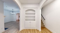 Located at The Preserve in Athens, Georgia, this two-story home showcases a thoughtfully designed interior that balances classic architectural details with modern finishes. Light wood-tone flooring flows throughout the main level, complementing the bright, white walls and crisp trim work that define the home's clean aesthetic.

The main living area features elegant arched doorways and a striking built-in bookcase with an arched upper display section and paneled lower cabinet doors, adding a refined architectural focal point. The adjacent kitchen is well-appointed with white shaker-style cabinetry, a herringbone tile backsplash, stainless steel appliances, and a peninsula topped with marble-look quartz countertops — ideal for both meal preparation and casual dining. Track lighting illuminates the workspace effectively.

Bedrooms are carpeted for comfort, with the primary bedroom distinguished by a tray ceiling and ceiling fan. A spacious walk-in closet with wire shelving provides generous storage. The bathroom features warm wood-toned cabinetry paired with matte black hardware and fixtures for a contemporary contrast. A dedicated laundry room with full-size washer and dryer and overhead cabinetry adds everyday convenience.