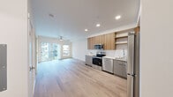 Located at 626 SW 151st St in Burien, WA, this thoughtfully designed one-bedroom, one-bathroom residence offers a contemporary open-concept layout with clean lines and modern finishes throughout. Light wood-tone flooring runs continuously across the entire unit, creating a cohesive and airy aesthetic.

The kitchen is a standout feature, showcasing warm wood-grain upper cabinetry paired with sleek grey lower cabinets, white quartz countertops, and a full suite of stainless steel appliances including a refrigerator, electric range, microwave, and dishwasher. Open shelving adds both function and visual interest to the space.

The living area flows naturally from the kitchen and is bathed in natural light from large sliding glass doors that open to a private balcony, offering views of the surrounding neighborhood. A ceiling fan provides additional comfort, while recessed lighting illuminates the space evenly.

The bedroom is a well-proportioned retreat featuring a large window that brings in ample natural light and a dedicated closet for storage. The bathroom is clean and modern, with a wide vanity featuring grey cabinetry, a white countertop, a large mirror, and light wood flooring that mirrors the rest of the unit. This residence offers a polished, move-in-ready living experience in a contemporary setting.