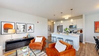 Located at 1780 W Orchard Rd in North Aurora, IL, this well-appointed two-bedroom, two-bathroom residence offers a comfortable and modern living experience across a single floor. The open-concept layout seamlessly connects the living room, dining area, and kitchen, creating an inviting and functional common space. Large windows in the living room flood the area with natural light while offering pleasant outdoor views, complementing the warm, contemporary aesthetic.

The kitchen is a standout feature, outfitted with stainless steel appliances including a refrigerator, range, and microwave. White upper cabinetry pairs with gray lower cabinets and light quartz countertops, while a peninsula with bar seating adds both prep space and casual dining convenience. Light wood-look flooring runs throughout the main living areas, adding warmth and continuity.

The dining area is bright and airy, positioned near a window with a peaceful outdoor view. The spacious primary bedroom features plush carpeting and natural light, while the second bedroom offers a similarly comfortable retreat. Each bathroom is finished with quartz vanities, gray cabinetry, and wood-look tile flooring. Both bedrooms are served by dedicated closets, providing practical storage. This residence balances modern finishes with a clean, neutral palette throughout.