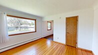 Located at 2080 Coon Rapids Blvd NW in Coon Rapids, Minnesota, this two-bedroom, one-bathroom unit offers a practical and efficient layout across a single floor. The space is defined by warm hardwood flooring that flows consistently through the living areas and bedrooms, complemented by classic oak wood trim and door accents throughout.

The primary bedroom is a generously sized room featuring two wood-trimmed windows that invite abundant natural light and offer views of the surrounding greenery. A closet with solid oak doors adds functional storage. The second bedroom is a more compact space, also with hardwood floors, a closet, and direct access to the full bathroom.

The bathroom is well-appointed with a wood-framed vanity mirror, a single-basin sink with an oak cabinet base, and a shower-tub combination enclosed by a curtain. The kitchen features rich oak cabinetry extending to the upper walls, offering ample storage, along with a double stainless steel sink, laminate countertops, an electric range, and a full-size refrigerator. Dark hardwood flooring in the kitchen distinguishes it from the rest of the unit. Baseboard heating is present throughout, ensuring comfort year-round. The overall ambiance is warm and functional, with a cohesive wood-toned aesthetic tying the space together.