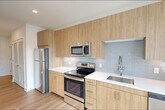 Located at 37 Orange Road in Montclair, NJ, this efficiently designed single-floor unit offers a clean, modern aesthetic defined by bright white walls, light-toned hardwood flooring, and an open layout that maximizes the available living space.

The kitchen is a standout feature, outfitted with flat-front wood-grain cabinetry extending to ceiling height, crisp white quartz countertops, a light blue subway tile backsplash, and a full suite of stainless steel appliances including a range, microwave, refrigerator, and dishwasher. A large window floods the kitchen with natural light and provides an outdoor view, enhancing the sense of openness.

The bedroom is a calm, well-proportioned space with warm hardwood flooring, clean white walls, and a built-in closet with integrated shelving and hanging rods, offering practical storage.

The full bathroom is finished to a high standard, featuring large-format light tile flooring, white horizontal wall tile in the tub/shower surround, a chrome grab bar, and a dedicated vanity area with a wood-cabinet base, white countertop, undermount sink, a large mirror, and modern LED vanity lighting. A recessed access panel in the hallway adds a practical, unobtrusive utility element. Overall, the unit presents a cohesive, contemporary design ideal for modern living.