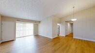 Located at 38360 Tamarac Blvd in Willoughby, Ohio, this single-floor 2-bedroom, 2-bathroom residence offers a thoughtfully designed layout with a clean, neutral aesthetic throughout. The spacious living room features warm hardwood-style flooring, a textured ceiling, and a large sliding glass door fitted with vertical blinds that flood the space with natural light and provide outdoor access. Adjacent to the living area, the kitchen is outfitted with white shaker-style cabinetry, light countertops, stainless steel appliances including a dishwasher and range, and a window above the sink for added brightness. Both bedrooms are carpeted and include closets — one bedroom features a standard reach-in closet with built-in shelving, while the primary bedroom offers generous proportions and natural light via a window with blinds. The two bathrooms are finished with hardwood-style flooring, white vanities with undermount sinks, framed mirrors, and grab bars for added convenience. A dedicated laundry room with wire shelving and washer/dryer hookups adds practical functionality. A central hallway connects all rooms, creating a logical and efficient flow throughout the home.