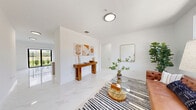 Located at 2301–2399 E Fourth Ave in Hialeah, FL, this well-appointed single-story unit offers a thoughtfully designed open-concept layout with 1 bedroom and 2 full bathrooms. Throughout the home, polished marble-look tile flooring creates a seamless, bright aesthetic that reflects natural light from large black-framed windows. The combined living and dining area is generous and airy, with clean white walls and an open flow that connects effortlessly to the kitchen. The kitchen features sleek gray cabinetry, white quartz countertops, stainless steel appliances including a range, microwave, and dishwasher, and an angled peninsula that provides additional prep and dining space. A separate family room offers additional living flexibility. The bedroom is comfortably sized, bathed in natural light, and includes a full-panel closet. Additional storage is provided by four closets throughout the unit, including a walk-in style closet with wire shelving. The two bathrooms are finished with striking marble-patterned tile walls and floors, with one featuring a soaking tub. A dedicated laundry area and a private patio complete the floor plan, offering outdoor access and a functional lifestyle layout ideal for South Florida living.
