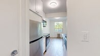 Located at 286 Finch Avenue West in North York, Toronto, this thoughtfully updated 2-bedroom, 1-bathroom unit offers a clean, modern aesthetic throughout. Light-toned hardwood-style flooring runs continuously across the entire floor plan, lending warmth and visual cohesion to every room.

The open living area is bright and airy, with multiple windows framing lush, tree-lined views and classic cast-iron radiators providing efficient, radiant heating. The space offers a comfortable and versatile layout suitable for both relaxing and entertaining.

The galley-style kitchen is well-appointed with white cabinetry, dark countertops, a subway tile backsplash, and a full suite of stainless steel appliances including a range, microwave, dishwasher, and refrigerator — combining a clean, contemporary look with practical functionality.

Both bedrooms are finished with the same light flooring and crisp white walls. The primary bedroom features a window with serene greenery views and a radiator, while the second bedroom offers a calm, neutral palette with easy access to hallway storage.

The bathroom is finished with classic white subway tile surrounding the bathtub and shower, complemented by grey floor tiles, a vanity with storage, and clean chrome fixtures — creating a timeless, polished look. Two hallways provide additional circulation and storage options throughout the unit.