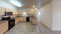 This single-floor residence offers a well-organized and functional layout designed for comfortable everyday living. The kitchen serves as a central hub, featuring light maple cabinetry with ample upper and lower storage, dark granite-style countertops, a double-basin stainless steel sink, and black appliances including a range and dishwasher. Large stone-tile flooring runs throughout the kitchen, which opens seamlessly into a spacious carpeted living area, creating an airy, open-concept feel ideal for both relaxing and entertaining.

The bedrooms are carpeted and generously sized, each benefiting from natural light provided by windows with blinds and baseboard heating for year-round comfort. The primary bedroom includes access to a walk-in closet outfitted with wire shelving and hanging rods for efficient storage organization.

The bathrooms are finished with matching stone-tile flooring and light maple vanity cabinetry topped with granite-style counters. One bathroom features a full tub-shower combination with clean white surroundings, while another vanity area includes a lighted mirror and additional tall storage cabinetry. A dedicated laundry area accommodates a full-size washer and dryer and includes wire shelving overhead, with the electrical panel conveniently housed in the same space.