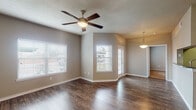 Located at 501 E Centerton Blvd in Centerton, Arkansas, this single-story residence offers a thoughtfully designed layout with consistent finishes throughout. The open living area makes a strong first impression with rich, dark hardwood-style flooring, a textured ceiling, and a ceiling fan with light kit. Multiple windows fitted with white blinds allow generous natural light to fill the space, creating a bright and welcoming atmosphere.

The kitchen is well-equipped, featuring white cabinetry, granite countertops, and black appliances including an electric range, over-the-range microwave, and refrigerator. A decorative display shelf adds a distinctive touch above the transition to the adjoining area.

The bedrooms are carpeted for comfort and each includes a ceiling fan. One bedroom features a walk-in closet with built-in shelving, while another offers mirrored sliding closet doors with interior shelving. Each room provides a calm, neutral environment with taupe-toned walls.

The bathrooms are finished with granite-topped vanities, white cabinetry, hardwood-style flooring, and tiled tub-shower combinations with curved curtain rods. Additional storage cabinetry above the toilet adds practical functionality.

Overall, the space presents a clean, neutral aesthetic with durable finishes and practical storage solutions throughout.