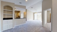 Located at 10246 Douglas Oaks Cir in Tampa, FL, this single-story, 3-bedroom, 1-bathroom home offers a well-designed open-concept layout filled with natural light. The spacious living room features vaulted ceilings, soft carpeting, a ceiling fan, and a sliding glass door that invites natural light and outdoor views, creating an airy and welcoming atmosphere.

The kitchen is thoughtfully designed with a pass-through breakfast bar, dark granite-style countertops, light wood cabinetry, a tile backsplash, black appliances including a range and refrigerator, and tile flooring. Track lighting illuminates the space efficiently, and a closet pantry provides ample storage.

The generously sized primary bedroom boasts vaulted ceilings, a ceiling fan, plush carpeting, natural light from large windows, and built-in shelving that adds both character and functionality. The additional bedrooms are carpeted and equipped with ceiling fans, with one featuring a walk-in closet with built-in shelving.

The bathroom is finished with tile flooring, a dark granite-topped vanity, white cabinetry, and a well-lit mirror. A dedicated utility room completes the home's practical layout. Three closets throughout provide abundant storage. Neutral tones and consistent finishes give the home a cohesive, move-in ready feel.