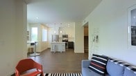 This thoughtfully designed multi-story home spans three floors, offering a well-organized layout with distinct living zones across each level. The main floor showcases an open-concept floor plan where the living, dining, and kitchen areas flow seamlessly into one another, creating a spacious and connected environment. Rich hardwood-style flooring runs throughout, grounding the space with warmth and continuity.

The kitchen is a standout feature, equipped with stainless steel appliances including a refrigerator, microwave, and range, complemented by a central island with bar seating and crisp white cabinetry contrasted by darker lower cabinets. Pendant lighting hangs above the island, adding a modern, polished touch. Recessed lighting throughout the main floor ensures the space is well-lit and inviting.

The living area is generously proportioned, providing ample room for comfortable seating arrangements. Natural light filters in through windows, brightening the open layout. A staircase connecting all three floors is centrally positioned, offering easy access between levels. The overall aesthetic is clean and contemporary, with neutral tones and modern finishes creating a cohesive, welcoming atmosphere throughout the home.