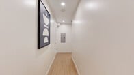 Located in the desirable West Los Angeles neighborhood of 90025, this thoughtfully designed 3-bedroom, 3-bathroom home maximizes every inch of its single-floor layout with smart, modern architecture. Light wood-grain luxury vinyl flooring flows through the clean, well-lit hallway, which features recessed lighting and a minimalist aesthetic that sets the tone for the rest of the space.

Each bedroom is efficiently appointed with built-in murphy beds that fold seamlessly into custom cabinetry, freeing up floor space while maintaining a polished look. The bedrooms feature windows that bring in natural light and views of the surrounding greenery, along with wall-mounted TVs integrated into warm wood built-ins.

The kitchen is a standout, outfitted with rich wood-tone cabinetry, white quartz countertops, stainless steel appliances including a professional-grade gas range, and under-cabinet lighting that creates a warm, functional cooking environment.

All three bathrooms are finished to a high standard, featuring large-format marble-look tile, glass-enclosed walk-in showers with built-in niches and seating, and vanities with warm wood cabinetry paired with white stone countertops. The space also includes an in-unit laundry area, completing this efficient yet refined Los Angeles residence.