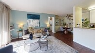 Located at 38034 Village Common in Fremont, CA, this single-story residence offers a thoughtfully designed layout that balances comfort and functionality. The open-concept living and dining area serves as the heart of the home, characterized by rich hardwood-style flooring, teal accent walls, and a ceiling fan overhead. A sliding glass door floods the space with natural light and provides direct access to a private outdoor patio. The living area flows seamlessly into the dining space, which is defined by warm lighting and an intimate atmosphere.

The galley-style kitchen features white cabinetry, neutral countertops, and full appliances including a range, refrigerator, microwave, and dishwasher, with hardwood-style flooring continuing throughout.

The primary bedroom is highlighted by a bold teal accent wall, plush carpeting, and an en-suite bathroom equipped with a wide vanity, generous counter space, and a well-lit mirror. A second bedroom offers carpeted flooring and bright natural light through a large window. The second bathroom includes a tub-shower combination with tile surround, while an additional bathroom features a glass-enclosed walk-in shower. Together, these spaces create a cohesive, well-appointed home.