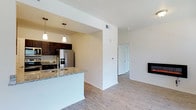 This well-appointed single-floor residence offers a thoughtfully designed open-concept layout with consistent light wood-style flooring throughout. The kitchen is a standout feature, showcasing rich dark espresso cabinetry, granite countertops, stainless steel appliances including a refrigerator with ice maker, electric range, microwave, and dishwasher. A peninsula with a built-in sink and pendant lighting connects the kitchen seamlessly to the living and dining areas, enhancing the open flow of the space. The living room is generously sized, bathed in natural light through large windows with blinds, and anchored by a sleek wall-mounted electric fireplace. A glass door leads to a private balcony, extending the living space outdoors. The bedroom is bright and airy, featuring a ceiling fan, a large window, and access to a spacious walk-in closet outfitted with wire shelving and storage baskets on all sides. The bathroom features dark cabinetry with granite countertops and durable wood-style flooring. A dedicated laundry nook with upper cabinetry and washer/dryer hookups adds everyday convenience. Clean white walls and an overall neutral palette lend the space a fresh, modern aesthetic throughout.