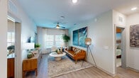 Located at 700 SE Veranda Pl in Port Saint Lucie, FL, this thoughtfully designed 2-bedroom, 3-bathroom residence offers a comfortable and modern single-floor layout. The open-concept kitchen is a standout feature, boasting granite countertops, a large island with bar seating illuminated by pendant lighting, stainless steel appliances, subway tile backsplash, and a two-tone cabinet design combining white uppers with warm wood-toned lowers. The living room is bright and welcoming, with large windows that invite natural light, light wood-style flooring, and a ceiling fan overhead. The primary bedroom features a bold warm-toned accent wall, plush carpeting, a ceiling fan, and direct access to a private en-suite bathroom complete with a marble-tiled walk-in shower, dual-sink vanity with granite countertops, and wood cabinetry. The second bedroom is equally inviting, with soft blue-green accent walls, natural light from large windows, and a ceiling fan. A dedicated walk-in closet provides ample storage. Throughout the residence, neutral tones, modern finishes, and consistent design elements create a cohesive and polished ambiance suited for everyday living.