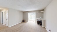 Located at 1720 Old St. Marks Church Rd in Burlington, NC, this single-floor, 2-bedroom, 2-bathroom residence offers a practical and comfortable layout. The spacious living room is a standout, featuring a corner fireplace with a white surround and built-in shelving, plush neutral carpeting, and a large window that fills the room with natural light. The kitchen is well-equipped with rich dark wood cabinetry, granite-style countertops, black appliances including a range, dishwasher, and refrigerator, and durable hardwood-style flooring. Both bedrooms are carpeted and include ceiling fans for added comfort, with the primary bedroom offering a generous walk-in closet and direct access to a private bathroom. The two bathrooms are finished with granite-topped vanities featuring undermount sinks and dark wood cabinetry; one bathroom includes a full tub-shower combination. A dedicated laundry room adds convenience to the layout. With four closets total throughout the unit, storage is plentiful. The neutral color palette and textured ceilings throughout lend a clean, cohesive feel to the entire space.
