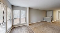 Located at 450 Johnny Mercer Blvd in Savannah, GA, this single-floor, 2-bedroom, 2-bathroom residence offers a well-organized layout with comfortable living spaces throughout. The living room serves as the heart of the home, highlighted by a tile-surround fireplace with a classic brass-framed glass door and plush carpeting underfoot. Large windows with blinds invite natural light, creating a bright and welcoming atmosphere. The living area transitions seamlessly to hardwood-style flooring near the kitchen, which features crisp white shaker cabinetry, light granite-style countertops, a stainless steel range, dishwasher, and refrigerator, all illuminated by stylish track lighting overhead. Both bedrooms are carpeted and generously sized, each equipped with ceiling fans, natural light from windows, and ample closet space via full-panel bifold doors. The primary bedroom offers an especially spacious feel with dual closets. Each of the two bathrooms includes a full tub-shower combination with a curved curtain rod, a toilet, and a vanity with granite-style countertops. Wood-look tile flooring in the bathrooms adds a cohesive, modern touch. Neutral gray walls and textured ceilings are consistent throughout, lending the space a clean, uniform aesthetic.