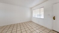 Located at 525 N Carolina Dr in El Paso, Texas, this two-bedroom, one-bathroom single-story home offers a straightforward and functional layout. Light-colored ceramic tile flooring runs consistently throughout every room, contributing to a clean and cohesive aesthetic. The living area is bright and open, with a front-facing window fitted with horizontal blinds that allow natural light to filter in. The kitchen is efficiently designed, featuring white cabinetry, a gas range with oven, a double-basin sink, and a window that brings in additional natural light. The layout keeps all essentials within easy reach. Both bedrooms are comfortably sized, each with windows that provide ventilation and daylight. Ceiling fans are present in the bedrooms, adding to the functional comfort of the space. The primary bedroom includes a sliding-door closet for storage, while painted block-style walls give the rooms a sturdy, durable character. The bathroom is neatly appointed with full-height beige tile surrounding a bathtub-shower combination, a toilet, and a window for natural ventilation. Central air conditioning with overhead vents serves the home. The overall design is clean and practical, well-suited for low-maintenance living in the El Paso area.