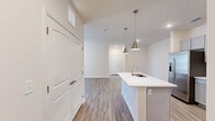 This well-appointed 2-bedroom, 2-bathroom single-floor residence offers a thoughtfully designed open-concept layout with modern finishes throughout. The combined kitchen, dining, and living area serves as the heart of the home, featuring a central island with a undermount sink, sleek white quartz countertops, and stylish pendant lighting. The kitchen is outfitted with gray shaker-style cabinetry, a white tile backsplash, and a full suite of stainless steel appliances. Wood-look luxury vinyl plank flooring extends throughout the main living areas, while a ceiling fan and access to an outdoor area enhance the living room's comfort and functionality. Both bedrooms are carpeted and feature ceiling fans and window blinds, with the primary bedroom offering a spacious walk-in closet with built-in wire shelving. The primary bathroom includes a standing shower with a glass door, while the secondary bathroom features a full tub-shower combo, both finished with brushed nickel fixtures and white vanities. Additional highlights include four closets, a dedicated pantry, an in-unit laundry area, and ample natural light throughout the space.
