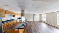 Located at 244 Worthington St in Springfield, MA, this single-floor, 2-bedroom, 2-bathroom residence offers a well-appointed and efficiently designed layout. The open-concept kitchen and living area serves as the heart of the home, showcasing rich dark hardwood flooring that flows throughout the space. The kitchen is a standout feature, equipped with warm honey-toned wood cabinetry, dark granite countertops, and a central island with a built-in cooktop and a stainless steel hood vent overhead. Stainless steel appliances, including a refrigerator, dishwasher, and in-unit washer, complete this functional kitchen. A drop ceiling with a grid tile design spans the kitchen and living area, adding a clean, finished aesthetic. The living area benefits from natural light via windows overlooking the surroundings, and a wall-mounted mini-split unit provides climate control. Both bedrooms are finished with the same dark hardwood floors and neutral-toned walls, offering a calm and versatile canvas. The primary bedroom includes its own mini-split unit and a window, while the second bedroom features dual windows that bring in additional natural light. Two hallways and a closet provide practical storage, and both bathrooms include tiled walls and standard fixtures.