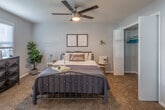 This single-floor residence offers a thoughtfully designed layout that balances comfort and functionality. The living room serves as the heart of the home, showcasing rich hardwood flooring, a ceiling fan with integrated lighting, and expansive windows fitted with blinds that flood the space with natural light while offering views of lush greenery outside. A patterned area rug, tufted sofa, marble-top coffee table, and accent armchair complete the inviting atmosphere.

The kitchen is well-equipped with deep-toned cabinetry, granite countertops, black appliances including a range and microwave, and a peninsula that creates an open, functional workspace. Decorative open shelving adds character and additional storage.

The bedroom provides a serene retreat with soft carpeted flooring, a ceiling fan, and a window that allows natural light in. The room comfortably accommodates a full-size bed and additional furniture, creating a cozy and restful environment.

The bathroom features a granite-topped vanity with an undermount sink, a large wall mirror, and clean tile flooring. Circular accent mirrors and greenery accents add a modern, polished touch to the space. Throughout the residence, neutral wall tones and consistent design choices create a cohesive and welcoming ambiance.