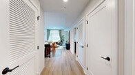 Located in the heart of Bethesda, MD, this well-appointed one-bedroom, one-bathroom residence offers a thoughtfully designed layout with modern finishes throughout. Light wood flooring flows seamlessly across the entire space, creating a warm, cohesive aesthetic.

The entry hallway is lined with multiple louvered-door closets, providing generous storage from the moment you step inside. The open-concept kitchen and living area serves as the heart of the home. The kitchen features two-tone cabinetry — white upper cabinets with navy lower cabinets, gold hardware accents, quartz countertops, stainless steel appliances, and a central island with seating, ideal for casual dining and entertaining. The living area receives abundant natural light through large windows dressed in elegant draping curtains, offering views of the surrounding neighborhood.

The bedroom is a calm, well-proportioned retreat with a large window that brings in natural light, light-toned walls, and direct access to a walk-in closet area. The bathroom is finished to a high standard, featuring large-format marble-look tile flooring and wall surround, a glass-enclosed walk-in shower, a dark vanity with gold hardware, and a white quartz countertop. A utility room completes the functional layout of this refined Bethesda residence.