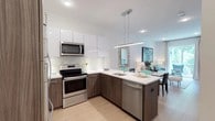 Located at 1177 Warburton Ave in Yonkers, NY, this thoughtfully designed single-floor residence blends modern aesthetics with functional living. The open-concept kitchen is a standout feature, showcasing two-tone cabinetry with high-gloss white upper cabinets and warm wood-grain lower cabinets, crisp white quartz countertops, a marble-style tile backsplash, and a full suite of stainless steel appliances. A sleek pendant light fixture anchors the kitchen peninsula, which flows seamlessly into the dining and living areas. The living room is bright and welcoming, with light hardwood flooring, recessed lighting, and a large sliding glass door that opens to a private balcony overlooking lush greenery. The two bedrooms are serene and well-proportioned, each featuring wide windows that invite natural light and views of the surrounding landscape, along with ceiling fans and light hardwood floors. The bathroom maintains the home's clean, contemporary style with white tile walls, a soaking tub with shower, white cabinetry, and a wall-mounted mirror. Throughout the residence, a neutral color palette, modern hardware, and quality finishes create a cohesive and refined atmosphere ideal for comfortable everyday living.