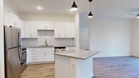 Located at 415 Curtis Pkwy SE in Calhoun, Georgia, this single-floor, 2-bedroom, 2-bathroom residence offers a thoughtfully designed layout with contemporary finishes throughout. The open-concept kitchen is a standout feature, showcasing crisp white shaker cabinetry, granite countertops, a subway tile backsplash, a central island with pendant lighting, and a full suite of stainless steel appliances including a refrigerator, electric range, over-the-range microwave, and dishwasher. The kitchen flows naturally into the living area, which features warm wood-look laminate flooring, a ceiling fan, and French doors that invite natural light and provide outdoor access. The spacious primary bedroom continues the wood-look flooring, includes a ceiling fan, and is served by a private bathroom with a glass-enclosed walk-in shower. The second bedroom also benefits from natural light through a window with blinds. A second full bathroom features a tub-shower combination with built-in shelving. Clean white walls, recessed lighting, and consistent flooring create a bright, cohesive aesthetic throughout the home, which also includes a closet and hallway for added storage and functionality.